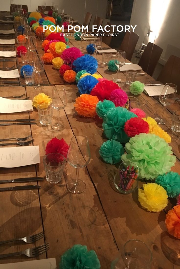 the table is set with paper pom - poms and place settings for dinner