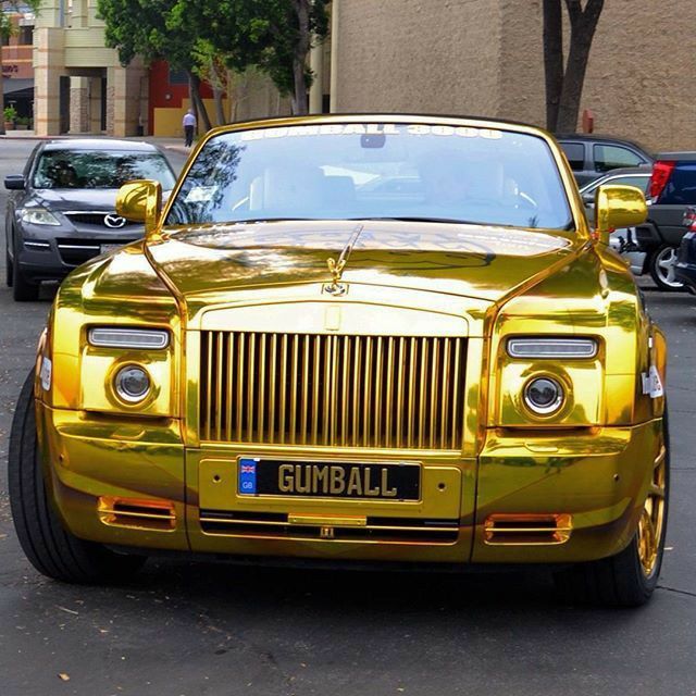 a gold colored rolls royce parked on the street