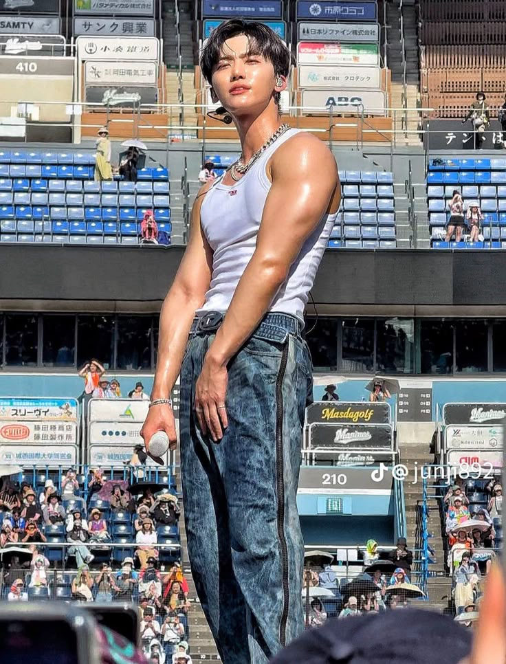 a man standing on top of a skateboard in front of a stadium filled with people