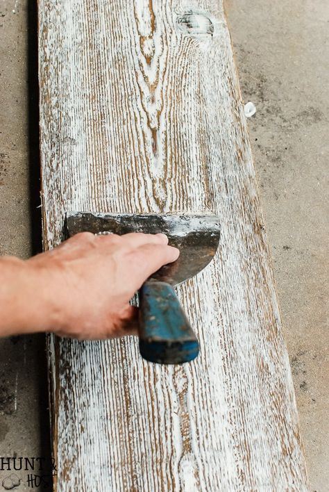 a person holding a hammer over a wooden plank