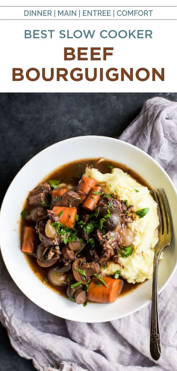 beef stew in a white bowl with mashed potatoes and carrots on the side