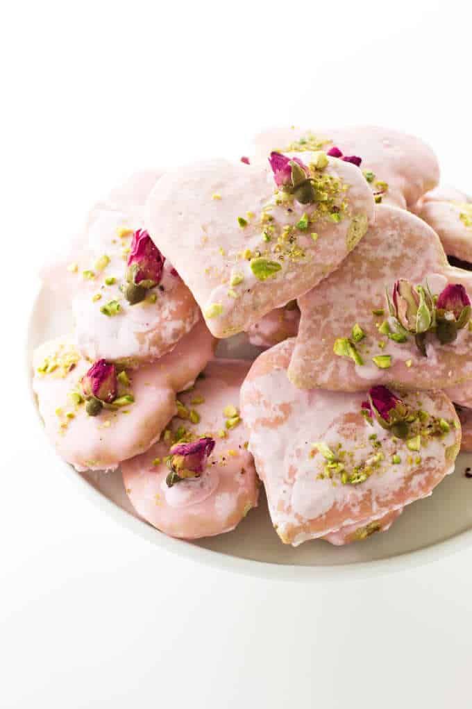 a white plate topped with pink donuts covered in icing