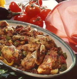 a plate full of chicken and peppers on a table with tomatoes in the back ground