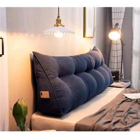 a blue pillow sitting on top of a bed next to a lamp