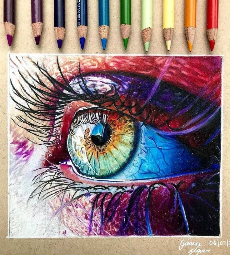 colored pencils are next to a drawing of an eye