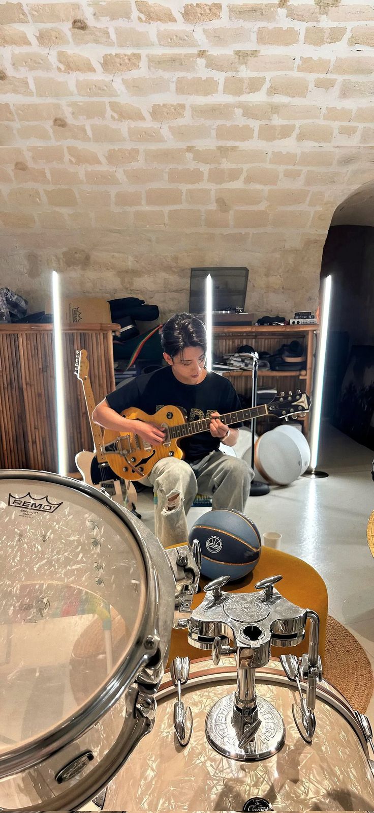 a man playing guitar in a room with drums