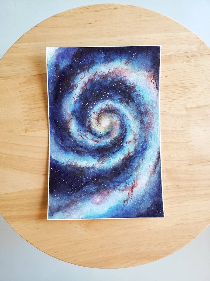 a wooden table topped with a painting of a spiral galaxy