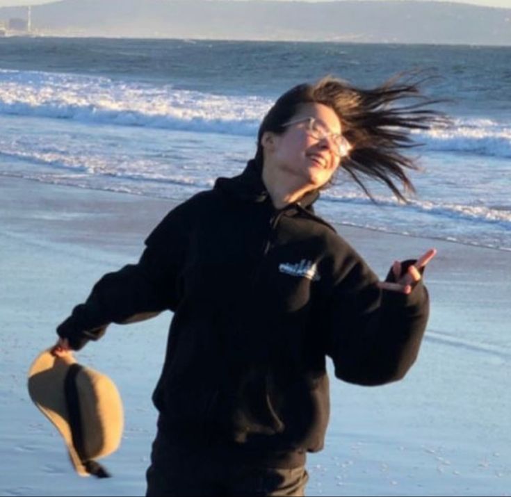 a woman is running on the beach with her hair blowing in the wind