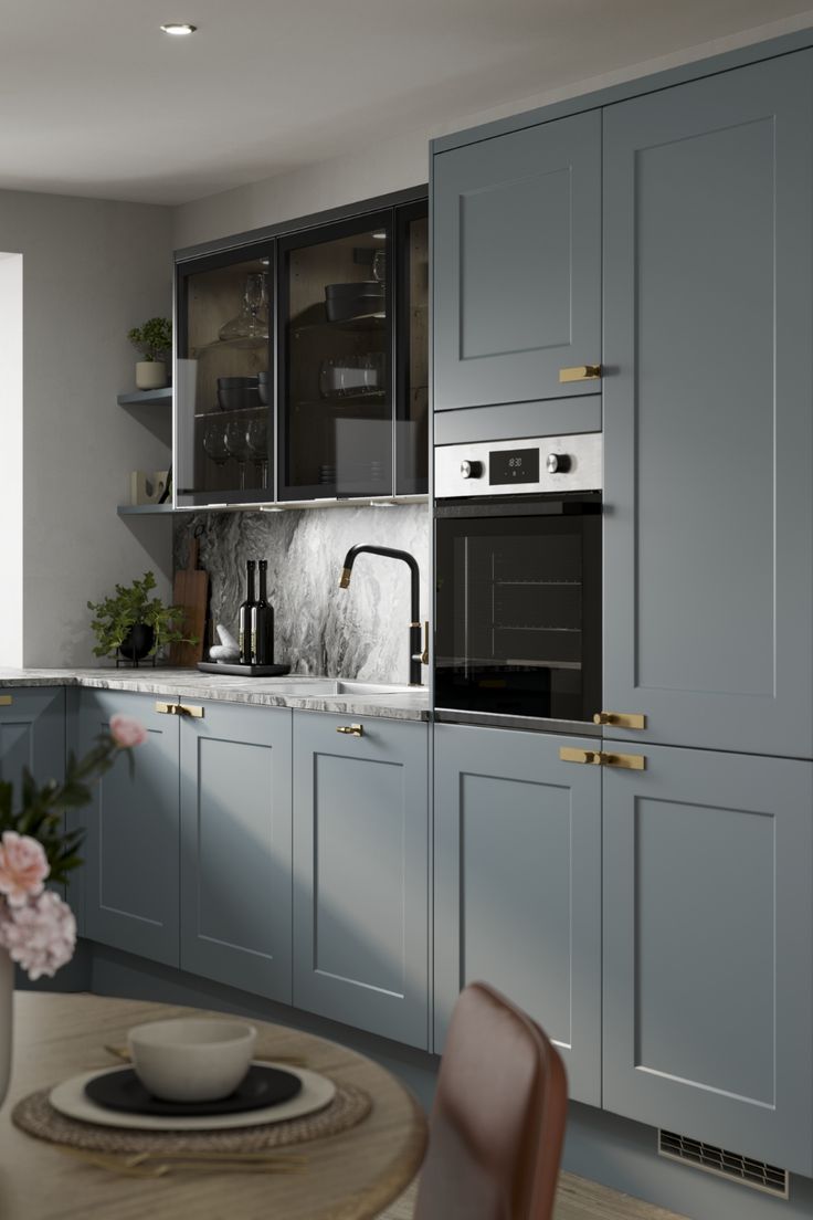 a kitchen with gray cabinets and white counter tops, along with a wooden dining table