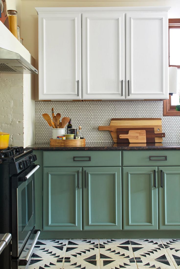 a kitchen with green cabinets and white cupboards on the countertop, black stove top oven and wooden cutting board