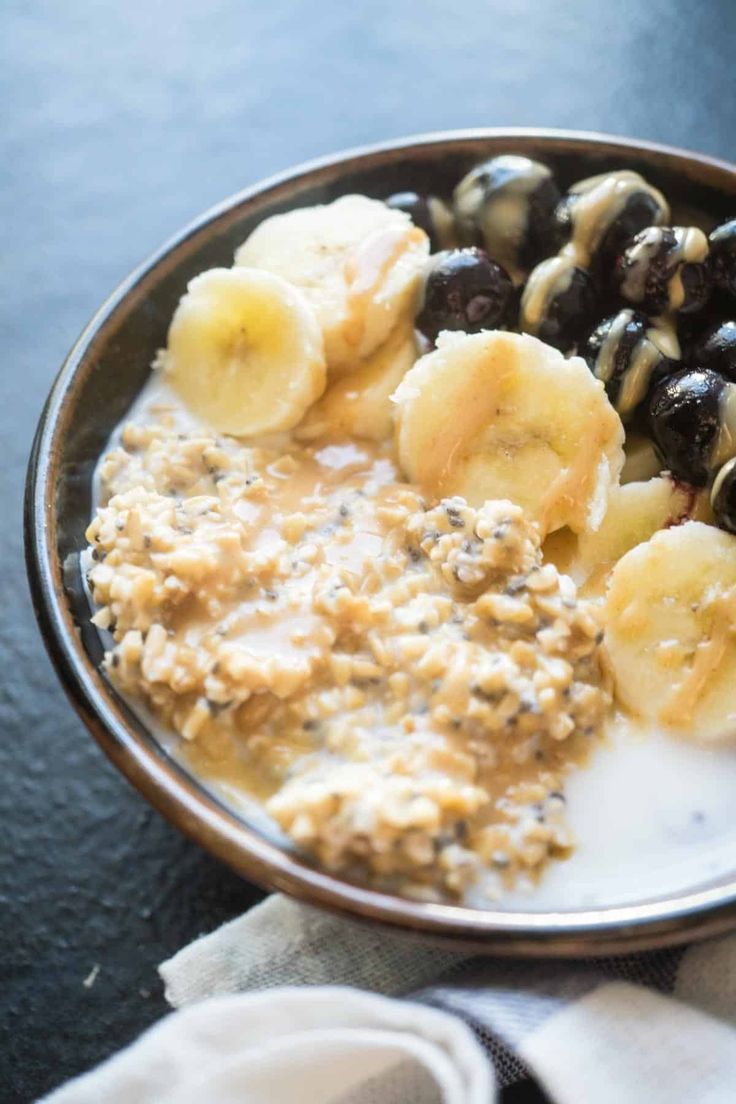 a bowl filled with oatmeal, bananas and raisins on top of a table