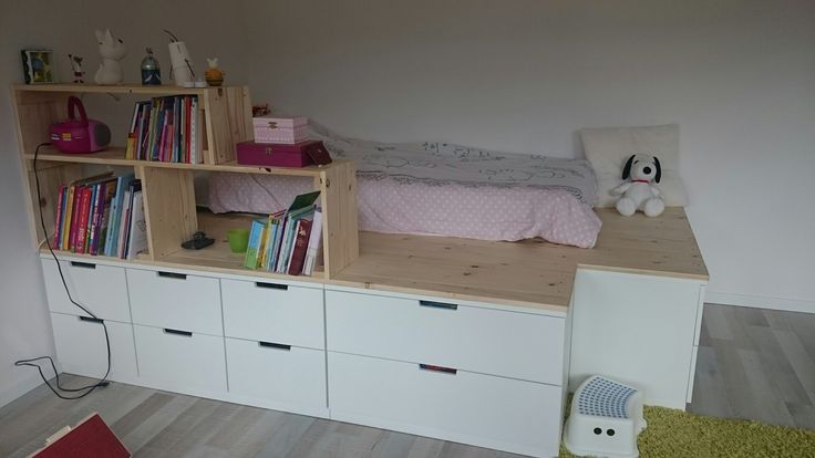 a room with bookshelf, bed and stuffed animal on the floor next to it