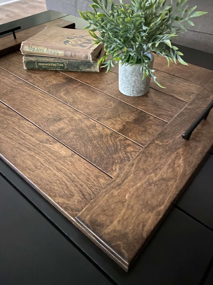 a wooden table topped with a potted plant and two books on top of it