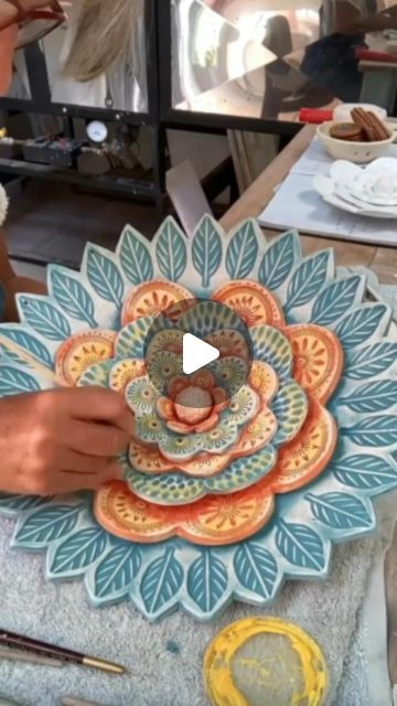 a woman is working on an art project with clay and paper flowers in front of her