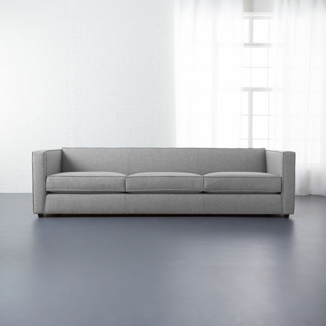 a couch sitting in front of a window on top of a hard wood floor next to a white wall