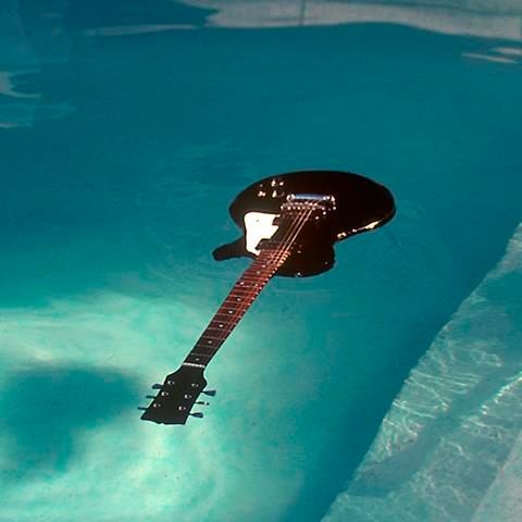 an electric guitar floating in a pool of water