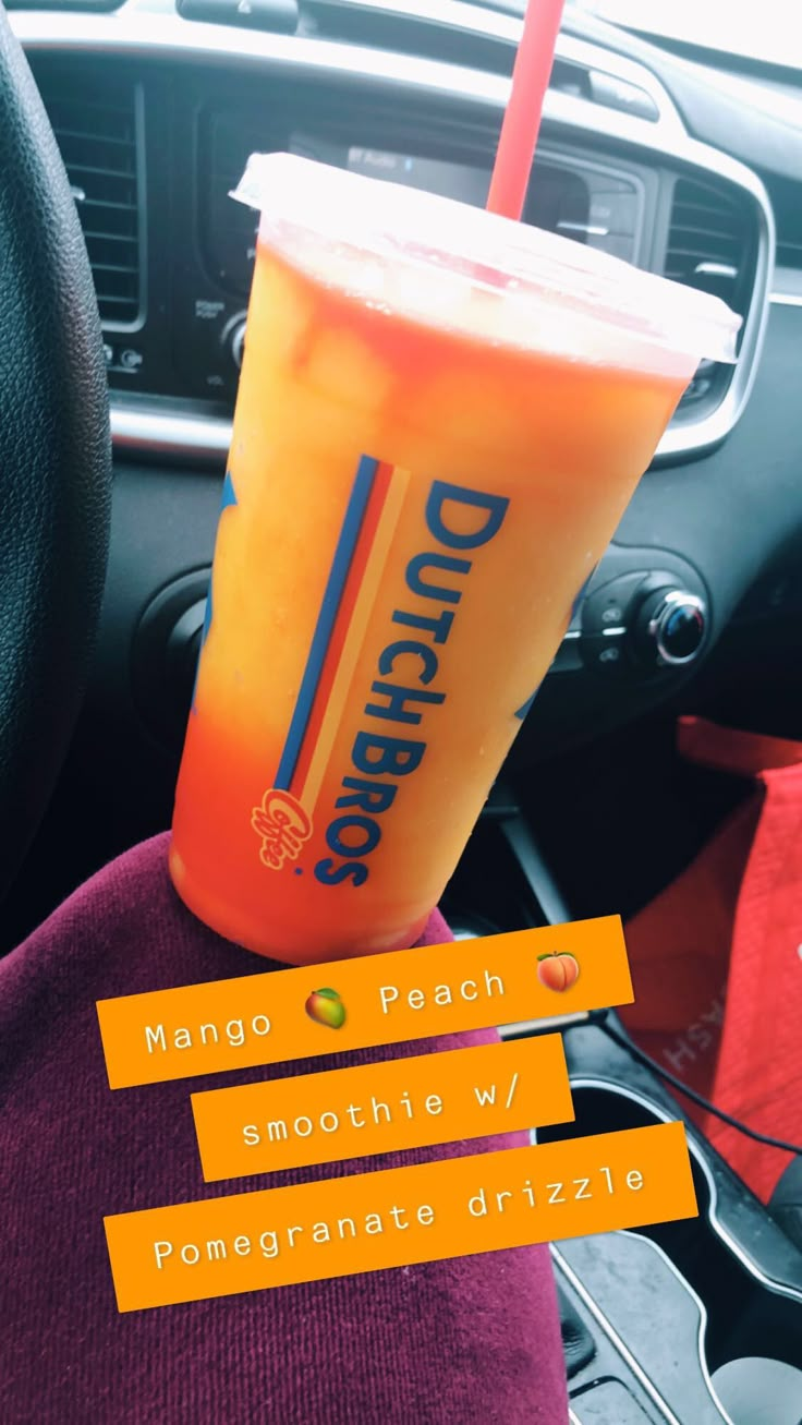 an orange drink sitting on top of a car dashboard