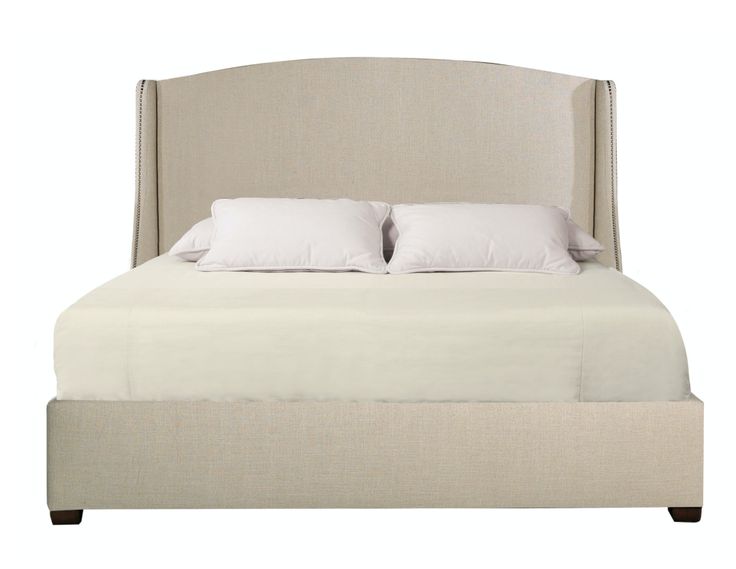 an upholstered bed with white pillows and linens on the headboard is shown