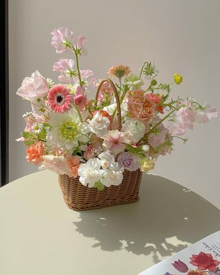 a basket filled with lots of flowers sitting on top of a table next to a book