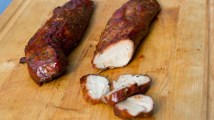 two pieces of meat sitting on top of a wooden cutting board