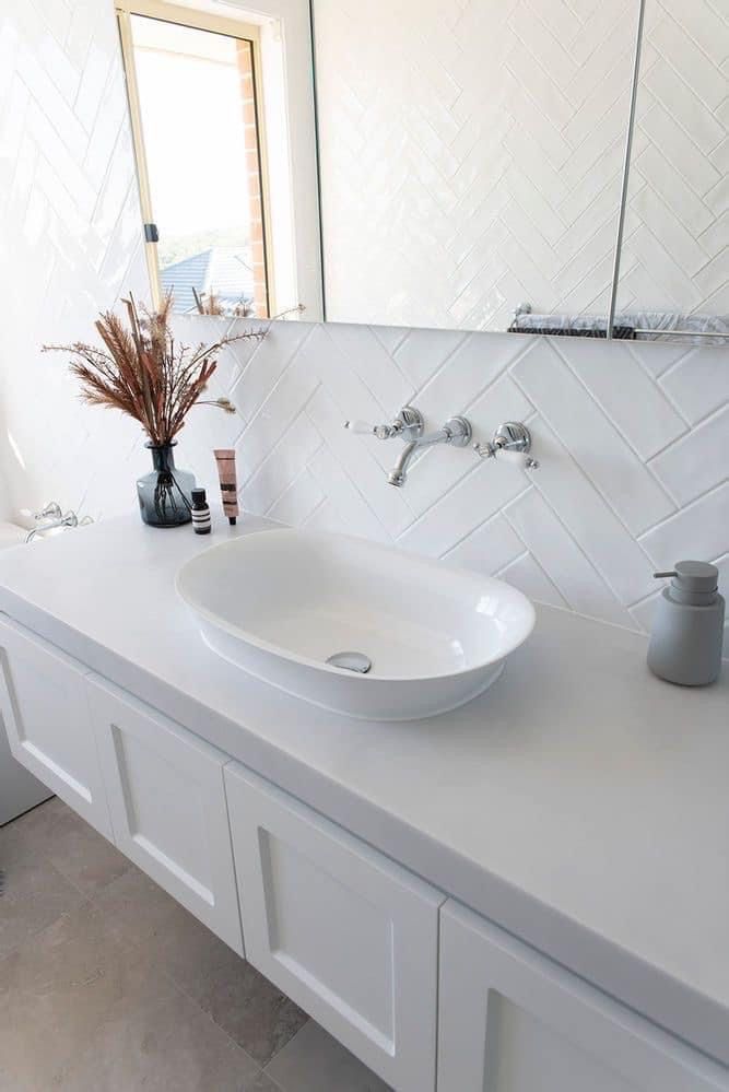 a white bathroom sink sitting on top of a counter next to a vase filled with flowers