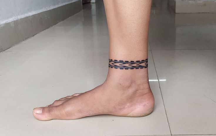 a woman's bare foot with a black and white bracelet on her left ankle