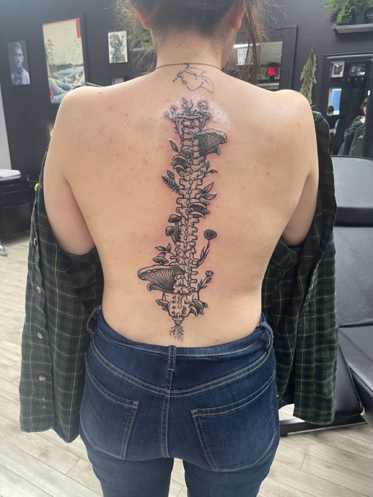 the back of a woman's body with tattoos on her upper and lower back