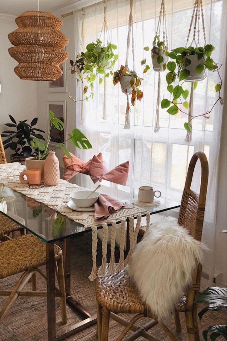 a dining room table and chairs with plants hanging from the windowsills in front of them