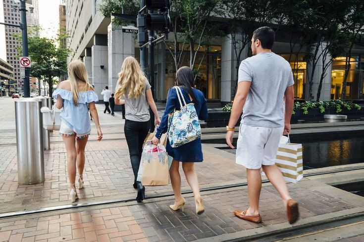 three people walking down the street with shopping bags in their hands and one person carrying a bag