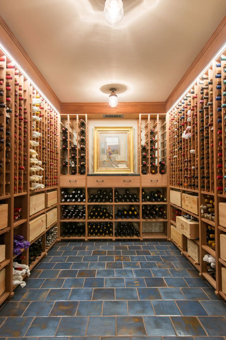 a wine cellar filled with lots of bottles and wooden shelves on either side of the room