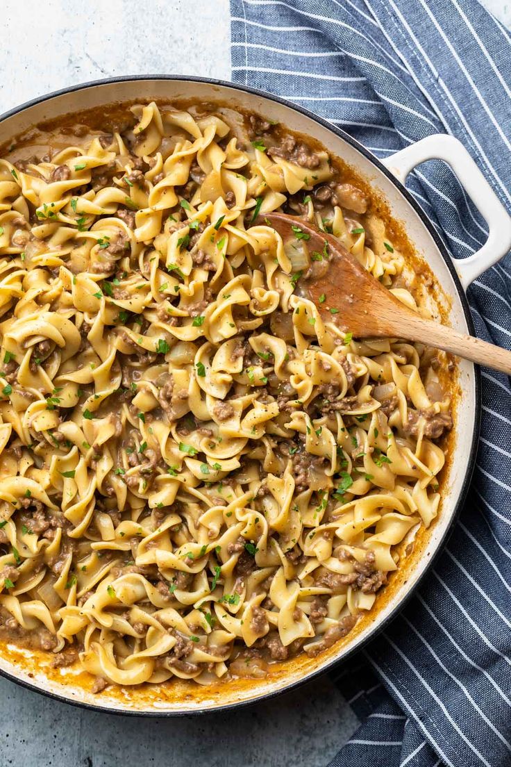 a skillet full of pasta with meat and cheese in it on a blue towel