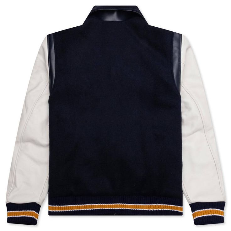 The BTFL Studios Letterman Jacket in Navy exemplifies the brand's commitment to blending heritage with modern design. Crafted from premium Japanese wool with Italian leather details, this jacket offers a luxurious take on the traditional American letterman style. It features a chenille embroidered patch, adding a touch of vintage charm. Each jacket is meticulously made, highlighting BTFL Studios' focus on quality and attention to detail. Premium Japanese wool Italian leather details Chenille emb Luxury Wool Outerwear With Ribbed Cuffs, Luxury Winter Outerwear With Contrast Collar, Luxury Navy Wool Outerwear, Luxury Navy Peacoat For Fall, Luxury Navy Long Sleeve Outerwear, Designer Winter Varsity Jacket For College, Luxury Outerwear With Contrast Collar And Long Sleeves, Designer Long Sleeve Outerwear For College, Luxury Varsity Jacket For Fall Streetwear