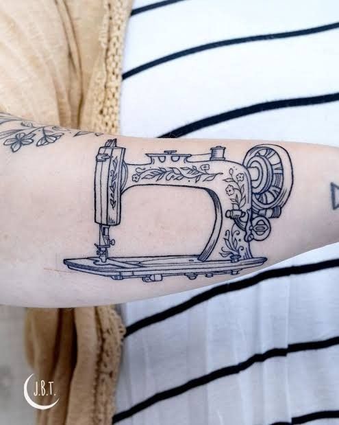 a woman with a tattoo on her arm holding a sewing machine