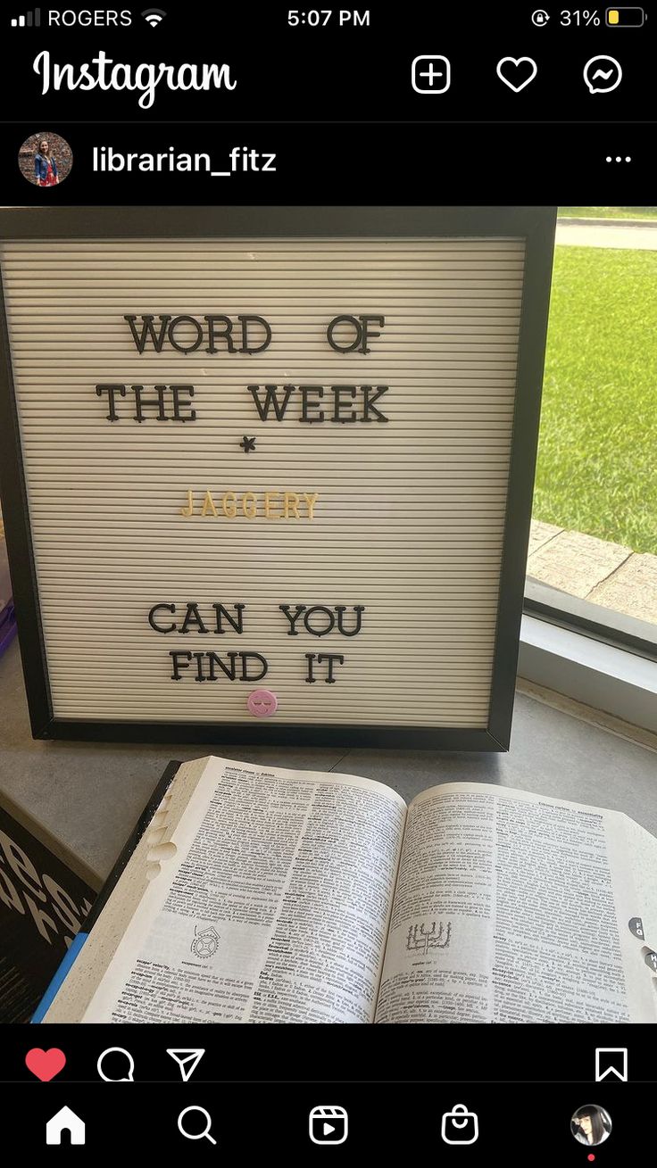 an open book sitting on top of a table next to a sign that says word of the week