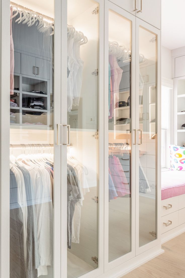 a closet with mirrored doors and clothes hanging on it's sides, in front of a bed