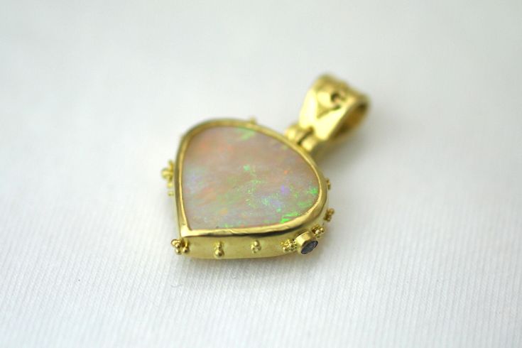 Prepare to be captivated by our Celestial Teardrop Opal Pendant, a true masterpiece of elegance and artistry. This breathtaking pendant features a magnificent 4.7 carat Australian Opal, elegantly shaped like a plump teardrop with its point gracefully facing downward. The opal is securely bezel set in lustrous 18kt gold, showcasing its mesmerizing play of colors. What sets this pendant apart is the meticulous attention to detail. Randomly speckled granulation adorns the sides, adding a touch of w Luxury Teardrop Cabochon Jewelry, Elegant Cabochon Teardrop Pendant Necklace, Elegant Teardrop Pendant Cabochon Necklace, Formal Teardrop Bezel Set Jewelry, Teardrop Cabochon Jewelry For Wedding, Elegant Teardrop Large Pendant Jewelry, Australian Opal, Opal Pendants, Bezel Setting