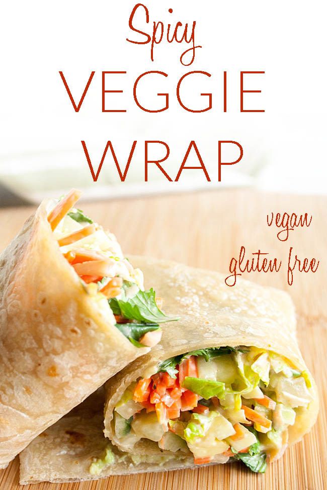 a wrap filled with veggies sitting on top of a wooden cutting board