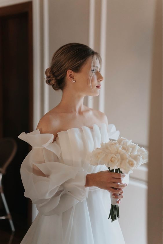 a woman in a white dress holding a bouquet of flowers and looking off to the side