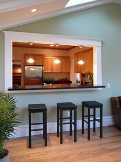 a living room with three stools and a kitchen in the backround behind it