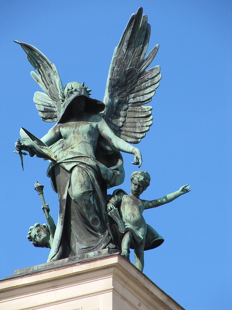 an angel statue on top of a building with two children around it and one is holding a bird