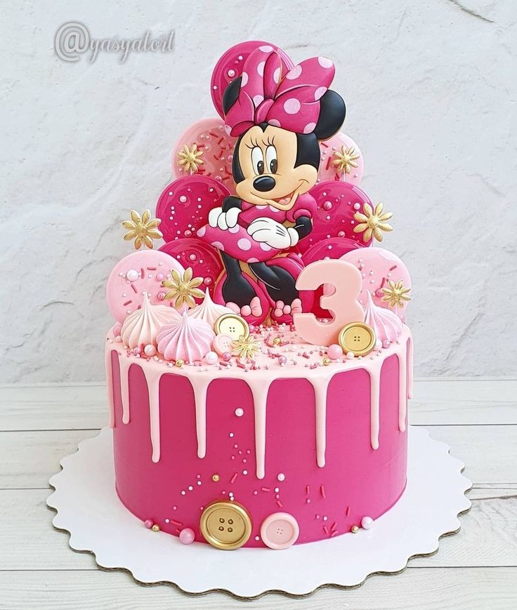 a minnie mouse cake with pink icing and decorations