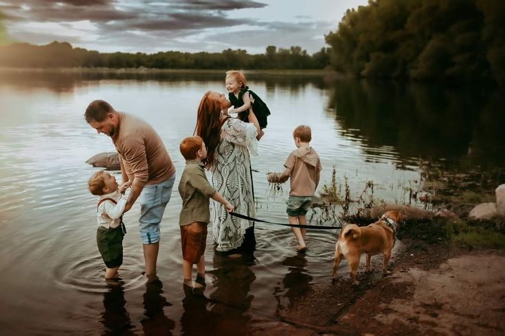 a group of people standing in the water with a dog on a leash next to them