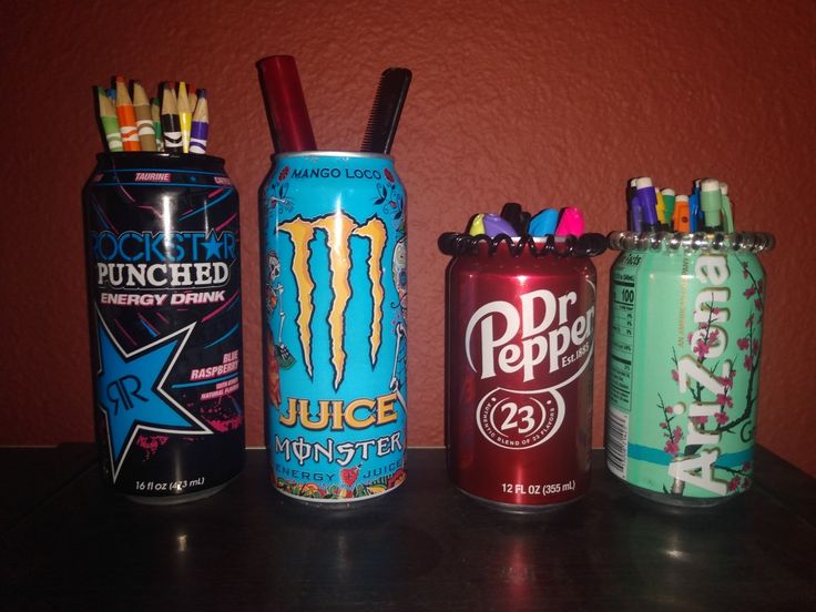 four cans are lined up next to each other on a table with pens and pencils in them