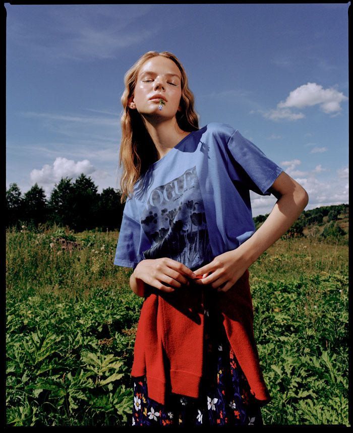 a woman standing in the middle of a field with her hands on her hips and eyes closed