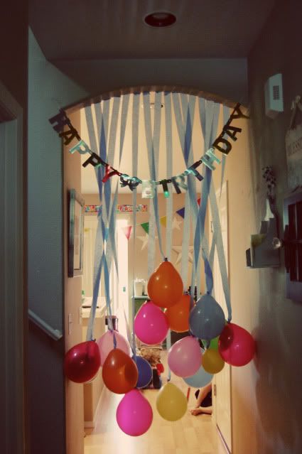 balloons and streamers are hanging from the ceiling in this hallway decorated for a birthday party