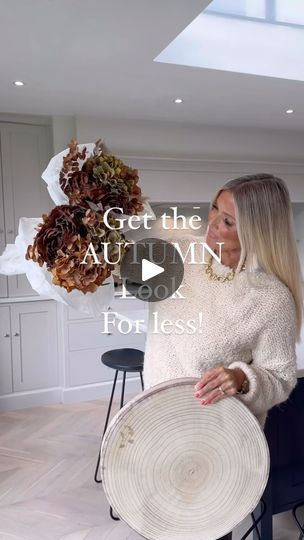 a woman holding a basket with flowers in it and the words get the autumn look for less