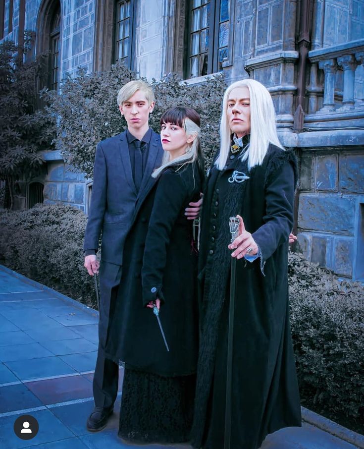 three people dressed in gothic clothing posing for a photo