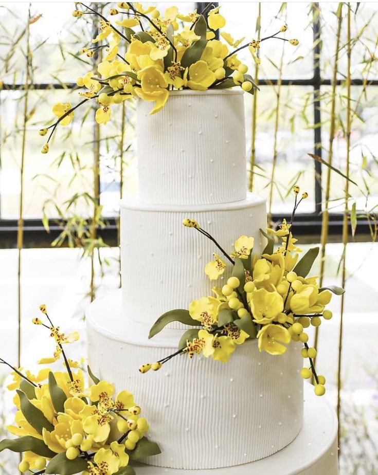 three tiered white cake with yellow flowers on top