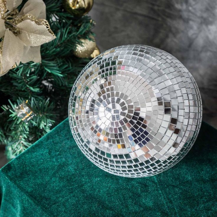 a disco ball sitting on top of a green table cloth next to a christmas tree