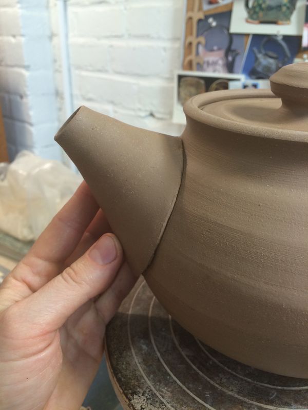 a person is holding a clay pot in their hand while they are working on it